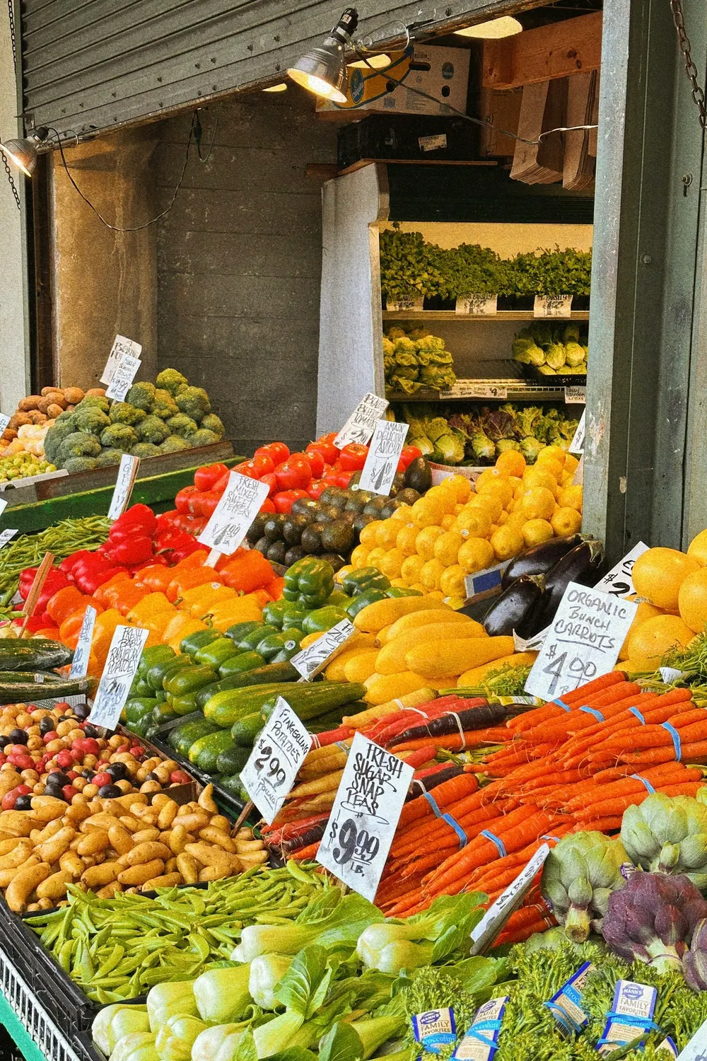 A greengrocer display of capsicums, carrots, beans and leafy vegetables with price cards