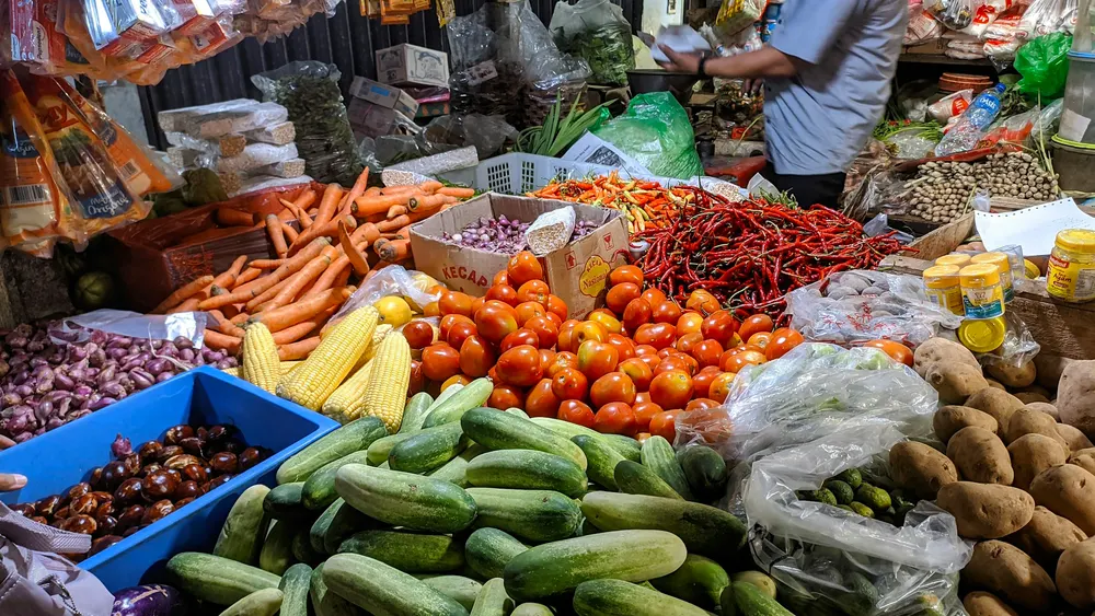 A market stall of carrots, tomatoes, corn, cucumbers, potatoes and chillies in crates